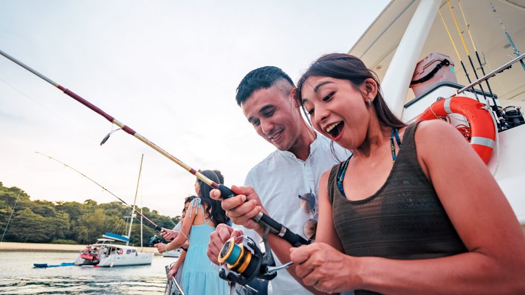 A happy couple holding a fishing rod on Mikanna yacht